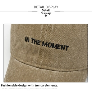 Detailed close-up of embroidered black letters on washed khaki vintage baseball cap