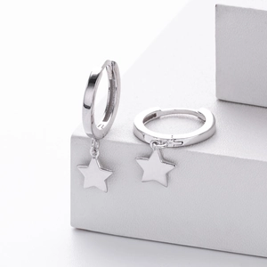 Detailed view of silver five-point star pendant earrings on white geometric props