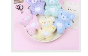 Close-up of five macaron-colored plush bears with heart patches and metal keychains