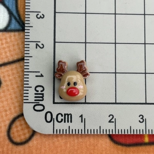 Macro view of small resin reindeer charm on measuring mat showing size and detail