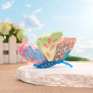 Colorful butterfly acetate hair claw clip with rhinestones on stone pedestal