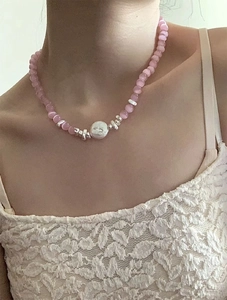 Detailed macro view of pink cat eye beads with irregular silver pendant on necklace