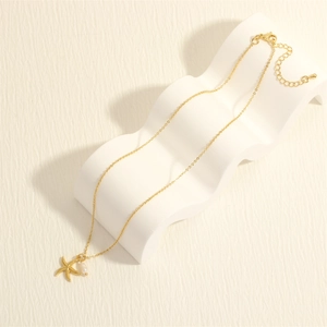 Detail view of 18K gold-plated starfish pendant with white pearl on adjustable chain