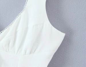 Détails de ce débardeur blanc col V avec bordure en dentelle festonnée et plis précis