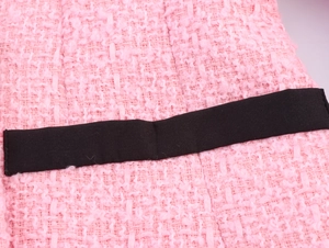 Nahaufnahme von rosa-weißem Tweedstoff mit schwarzem dekorativem Webband-Detail