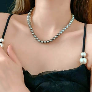 Close-up of elegant grey pearl necklace with high luster on model wearing black dress