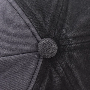 Close-up of the dark grey corduroy baseball cap top button and precision stitching detail