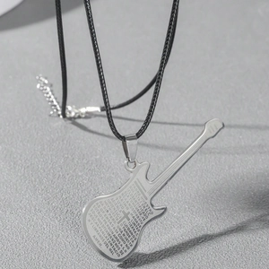 Macro shot of silver guitar pendant with Spanish Lord's Prayer engraving on black cord