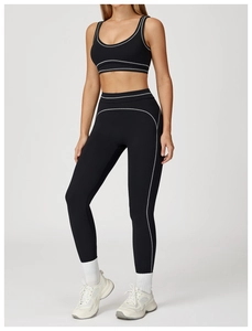 Détail d'un ensemble de yoga noir avec coutures contrastées blanches sur le haut et legging
