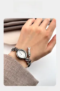 Detail of GEDI women watch with silver oval dial, chain strap, and small fish charm