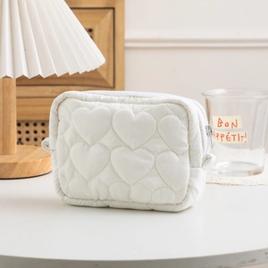 Detail of white quilted heart pattern cosmetic bag with high-quality metal zipper