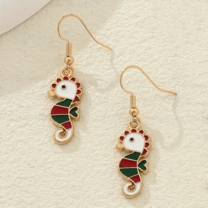 Gros plan de boucles d'oreilles hippocampe mignonnes en émail rouge et vert doré