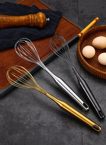 Three premium stainless steel whisks in gold silver and black on a dark kitchen stone