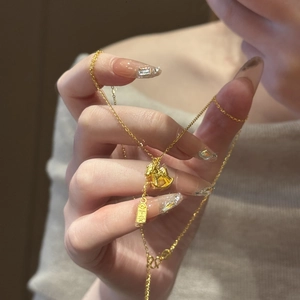 Close-up of a 24K gold plated rocking horse necklace with a Ping An charm on a fine chain