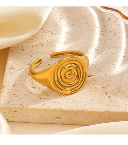 Macro detail of golden spiral twist ring displayed on a textured stone pedestal