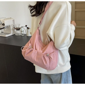 Pink nylon dumpling bag with drawstring details shown in a cozy cafe setting