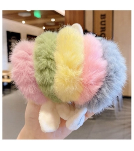 Close-up of a large plush hair claw clip featuring a multi-color faux fur patchwork design
