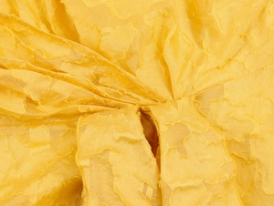 Macro shot of yellow textured fabric with floral jacquard pattern and subtle sheen