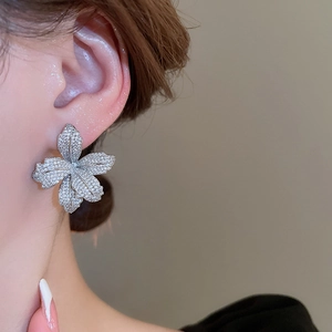 Close-up of elegant silver flower stud earrings with shimmering pavé cubic zirconia on model