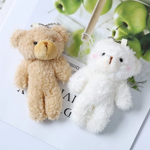 Macro detail of plush teddy bear charms in beige and white with soft curly fur texture