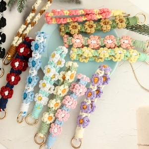 Detailed flat lay of colorful handmade woven daisy flower keychains on a light blue tray