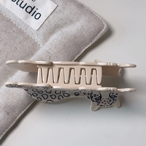 Detail view of leopard print hair claw clip in animal silhouette on white background