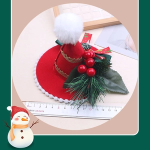 Dettaglio di un mini cappello di Natale rosso con pompon bianco e foglie verdi