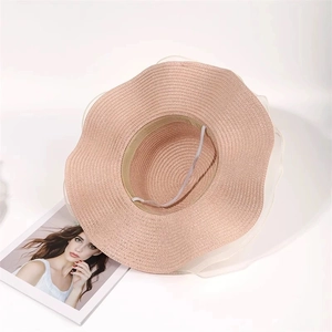 Pink straw sun hat featuring a wide wavy brim and translucent white mesh ribbon detail