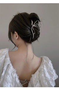 Detail of silver metallic butterfly claw clip worn on model's bun hairstyle