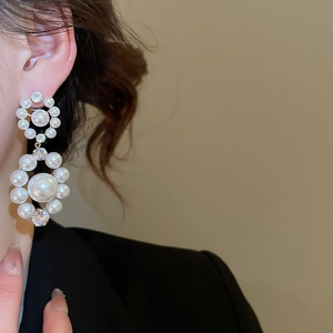 Détail de boucles d'oreilles doubles perles élégantes avec zircons sur un mannequin