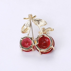 Detailed back view of a golden cherry brooch with red gemstones and a secure pin clasp
