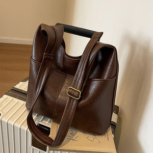 Retro dunkelbraune PU-Leder-Eimertasche auf weißem Koffer in minimalistischem Ambiente