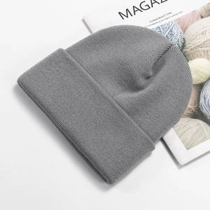 Detail of gray knitted beanie on magazine showing fine texture and ribbed cuff