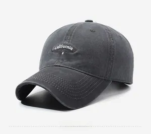 Detail view of washed cotton fabric and white California embroidery on dark grey baseball cap