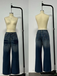 Detailed view of washed gradient denim with decorative stitching on loose-fit jeans