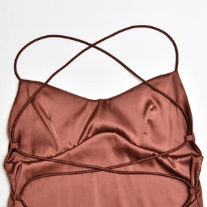 Gros plan détaillé de la robe en satin marron avec fines bretelles croisées et tissu lisse