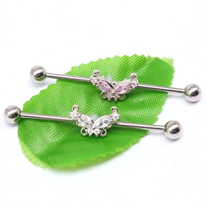 Detail view of butterfly industrial barbell earrings with pink and clear zircon crystals