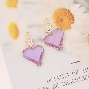 Macro detail of heart-shaped purple gemstone earrings with floral zircon accents