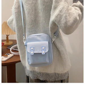 Detail of light blue mini canvas crossbody bag with white decorative buttons and front pocket