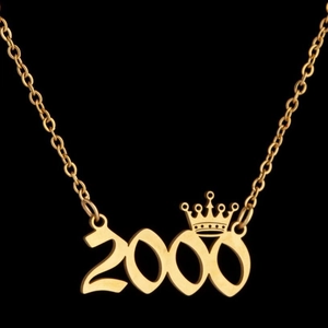Close-up of golden crown and 2000 year number pendant necklace on black background