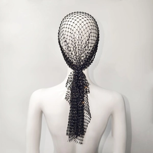 Dettaglio di un copricapo a rete nera con strass scintillanti e decorazioni di paillettes
