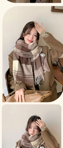 Close-up of brown plaid scarf showing soft fabric texture, fringe ends and decorative label