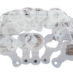 20-piece set of white translucent Christmas coffee stencils on a light wood background