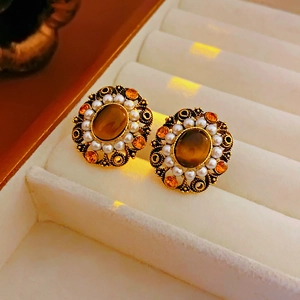 Macro shot of vintage gold earrings with oval amber stones and pearl border on velvet box