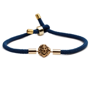 Adjustable dark blue braided rope bracelet with golden lion head charm on white background