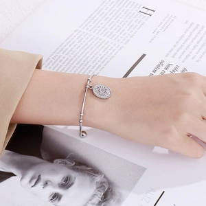 Détail d'un bracelet jonc en acier inoxydable argenté avec pendentif soleil sur un magazine