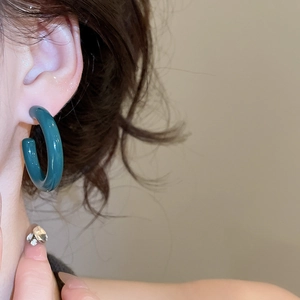 Close-up of model wearing thick dark green resin hoop earring with a smooth glossy finish