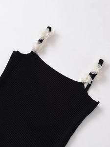 Close-up of black knitted top with elegant white floral lace embroidery on the shoulder straps