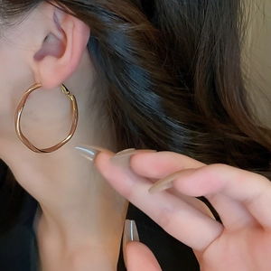 Detail shot of gold irregular wave hoop earrings showing polished texture and fluid design