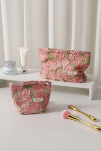 Detail of floral embroidery fabric on green toiletry bag with petal metal zipper pull